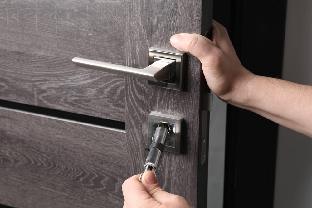 Secure Modern Door Handle Installation – Door Installation St Louis Close-up of a technician installing a modern door lock and handle on a dark wood door – Door Installation St Louis