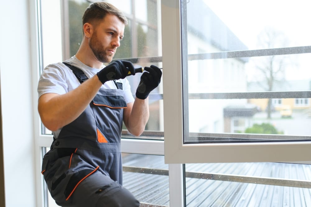 Male technician in work overalls adjusting a window frame with tools during an installation project – st louis mo window installation